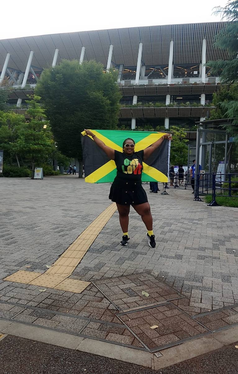 Chanise Henry lifts the Jamaican flag outside the Japan National Stadium on Sunday.