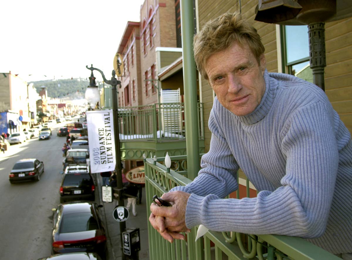 Robert Redford poses on a balcony along Main Street decorated with his Sundance Film Festival banners on January 17, 2003, in Park City, Utah. 