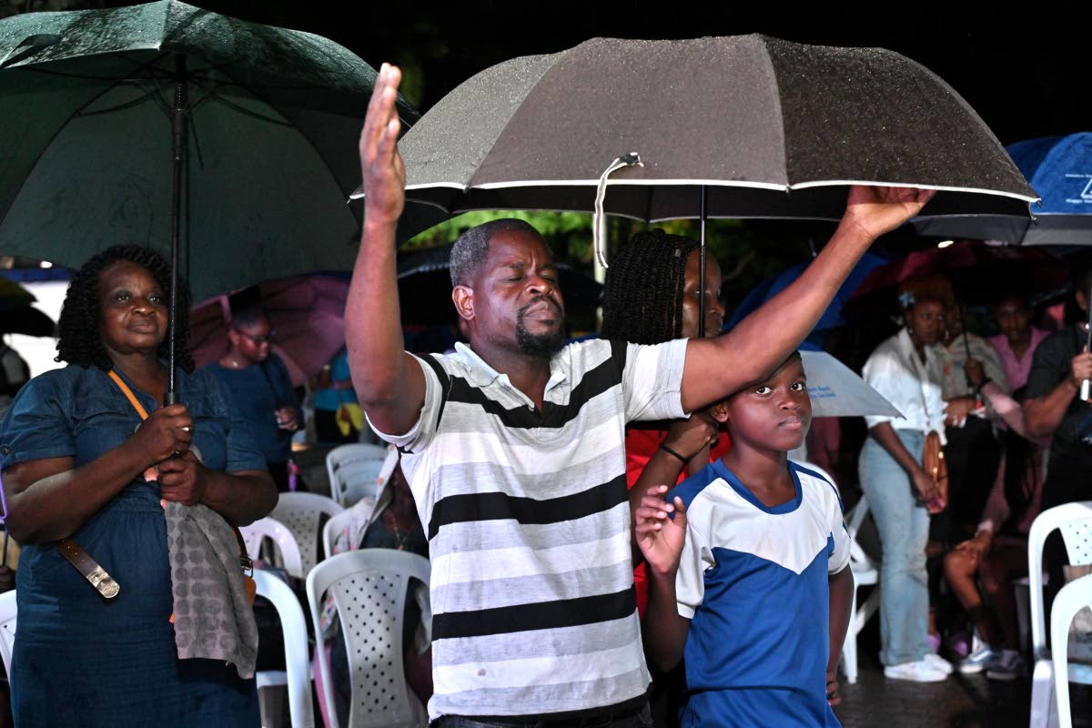 Sheltering under umbrellas, gospel fans enjoy the moment at the Jamaica Credit Union League /CUNA Caribbean Insurance Praise in the Park at Emancipation Park last Thursday.