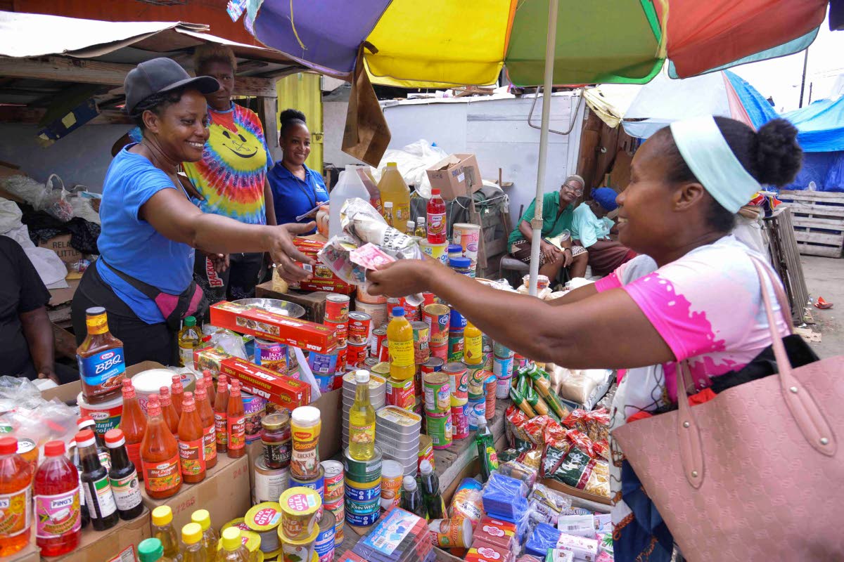 Shereen Clarke (left), a vendor along Spanish Town Road in the vicinity of the Coronation Market, sells an item to her customer, Nicole Chang (right).  