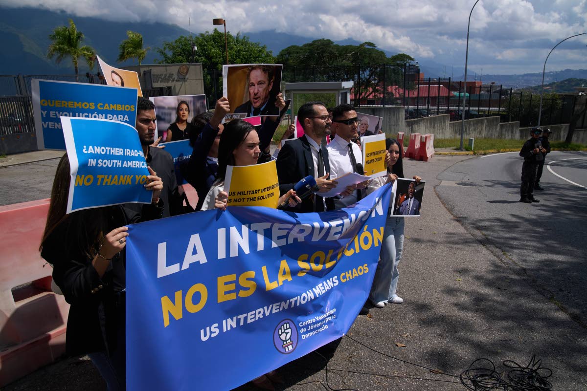 Members of the Venezuelan Youth Center for Democracy protest outside of the US Embassy  in Caracas, Venezuela, holding signs that read in Spanish "Intervention is not the solution", in reference to US warships operating in the Caribbean, on October 27, 202