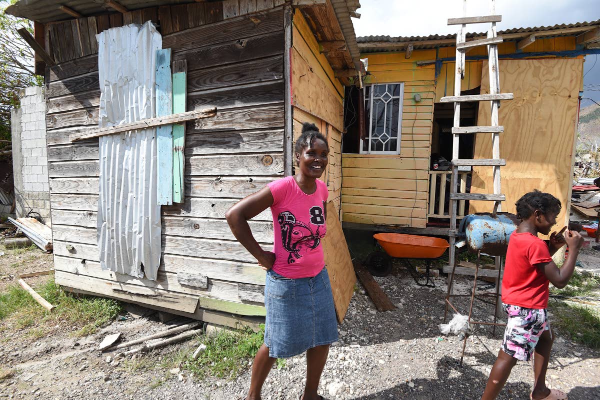 Retirement resident Suzetta Williams walks in front of her board house, one of the few wooden structures that survived Melissa’s strong winds.