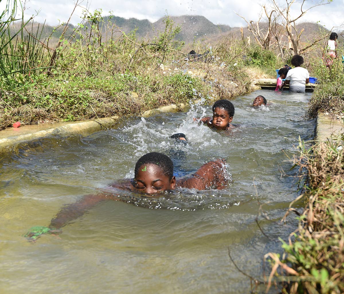 With their school damaged during Hurricane Melissa, boys swim in a canal in Shewsbury, Westmoreland.