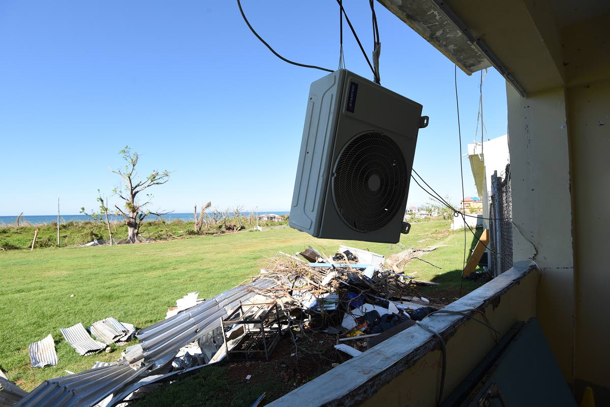 A dislodged air-conditioning unit hangs outside a classroom at Belmont Academy in Westmoreland following the passage of Hurricane Melissa in October last year.