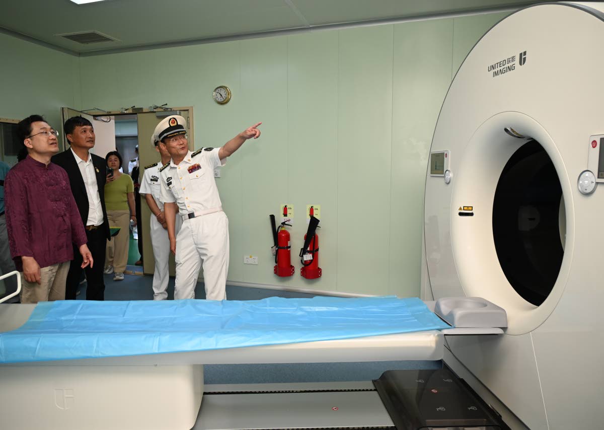 From left: Ambassador of the People’s Republic of China to Jamaica, Wang Jinfeng; Ziping Chen, chairman of the Fujian Association of Jamaica; and Li Min, crew member of ‘Ark Silk Road’ medical ship viewing a CT scan machine during a tour of the vesse