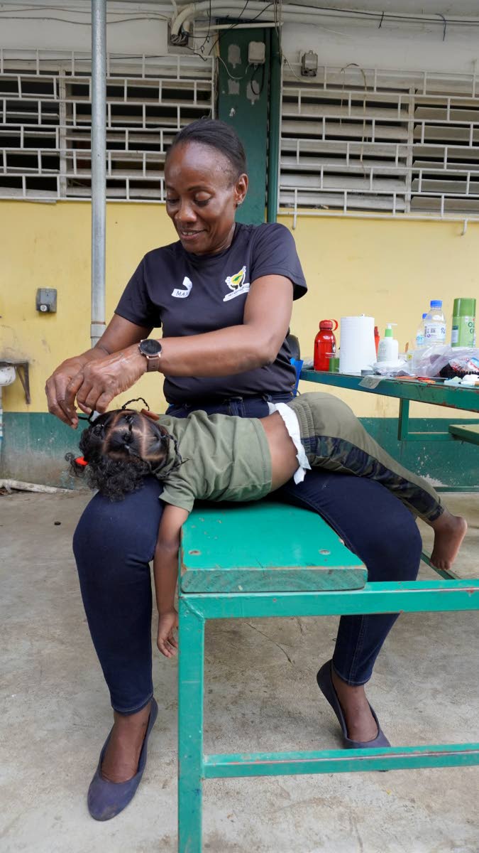 A United4GoodJA volunteer styles the hair of a young shelter resident in Westmoreland.