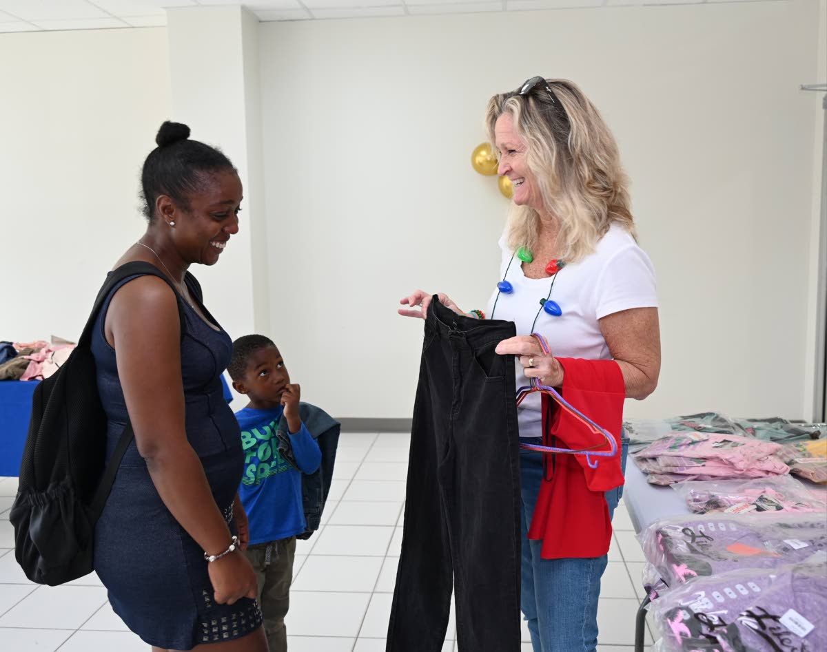 Lynda Langford (right), vice-president of Global Services Association of Jamaica (GSAJ), showcases clothing items to Savy and her son Josiah Singh during the Montego Bay Free Zone and GSAJ post-Hurricane Melissa Christmas Treat.