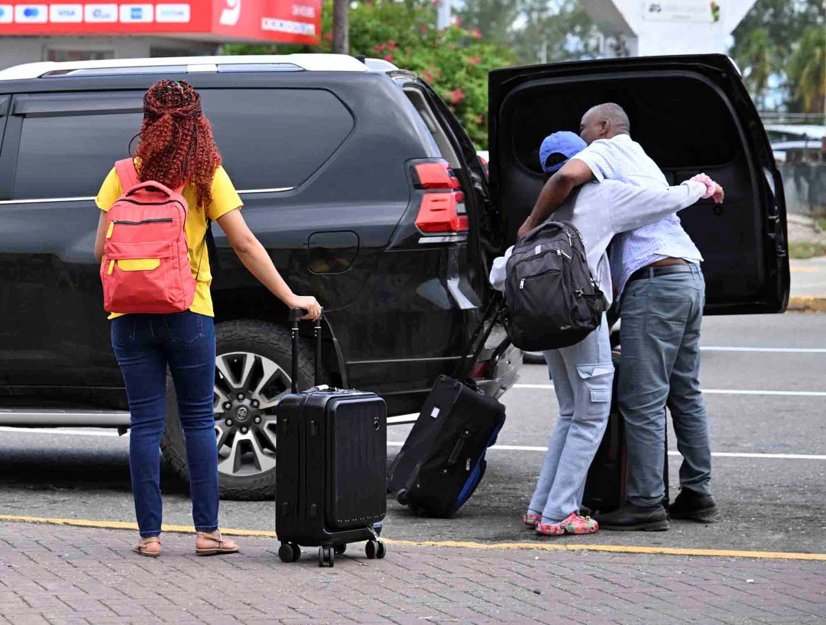 A traveller is greeted with a warm hug on arrival at the Norman Manley International Airport on Monday.