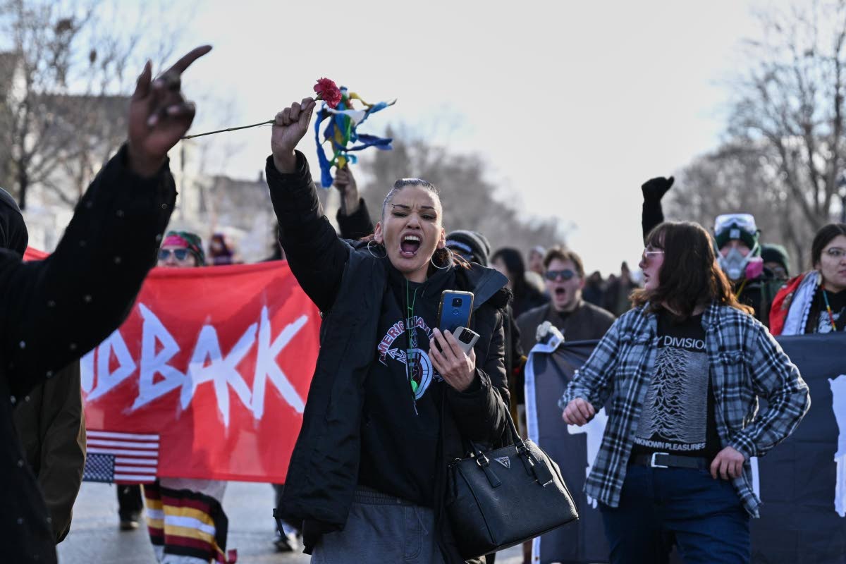 People protest as law-enforcement officers attend to the scene of the shooting involving federal law-enforcement agents yesterday in Minneapolis.