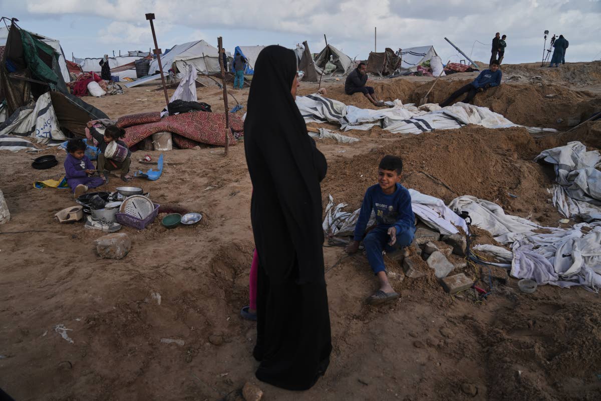 Palestinians inspect the damage at a displacement camp following an Israeli strike in Gaza City.