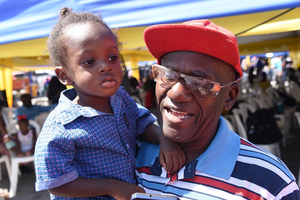 Liston Morrison (right), president of the International Community of Churches, who is visually impaired, holds his two-year-old son Mathias Morrison at the Ministry of Justice, Legal Aid Council’s Justice Fair for Persons with Disabilities in Spanish Tow
