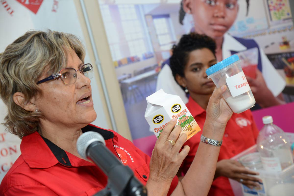 Deborah Chen (left), executive director of Heart Foundation of Jamaica, shows an example of a box drink and the equivalent sugar content, while Ponetta Nurse, advocacy officer of HFJ, looks on.