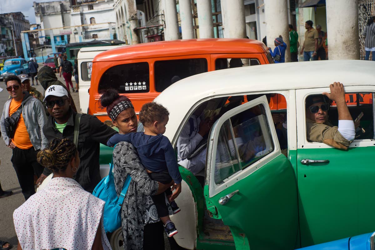 
People wait their turns to board shared taxis in Havana, Cuba, on February 6. The Jamaican students say transport costs have ballooned since the imposition of tighter sanctions on Cuba by the United States.