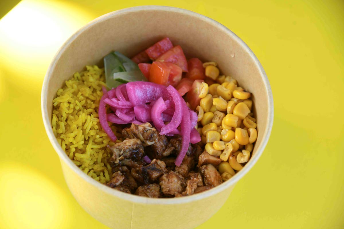 This yardi jerk bowl is built with coconut turmeric rice, jerk barbecued chicken, grilled corn, cucumber, grape tomatoes, pickled red onion, and a plantain Scotchy aioli.