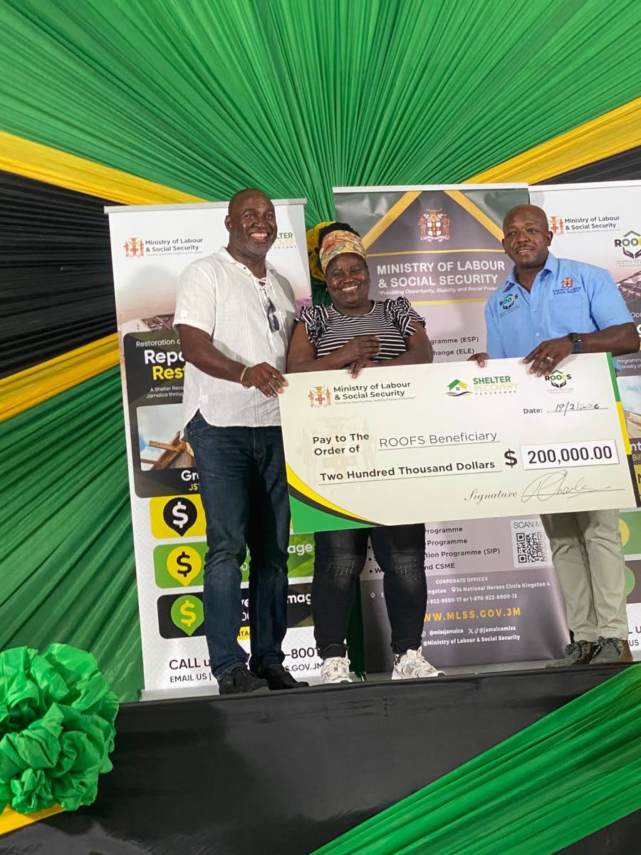 Sylvia Ferguson (centre) of Darliston, Westmoreland, beams as she receives a symbolic cheque valued at $200,000 under the Government’s Restoration of Owners or Occupants of Family Shelter (ROOFS) Programme, administered through the Ministry of Labour and
