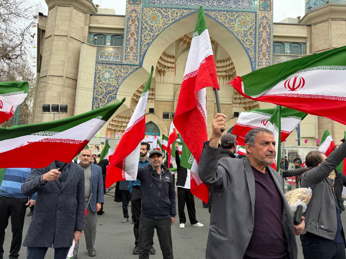 A group of men wave Iranian flags as they attend a demonstration in support of the government and against United States and Israeli strikes in Tehran, Iran on February 28, 2026. 