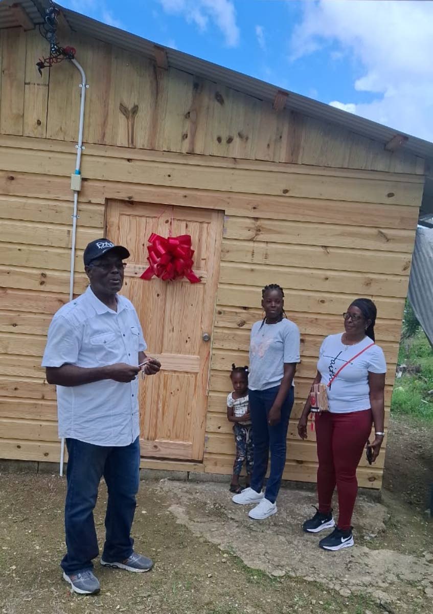 Bishop Donald McFarlane, pastor at New Foundation Christian Ministries, hands over a house to the new homeowner, Nickeisha Lewis, who was accompanied by one of her children, Shantary Thomas, and her mother, Violet Bailey.