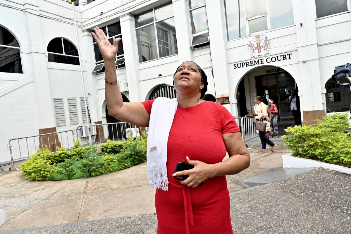 Sophia Lugg, mother of Donna-Lee Donaldson, raises her hand to thank God for showers of rain on leaving the Supreme Court in downtown Kingston after Noel Maitland was yesterday sentenced for the murder of her daughter.