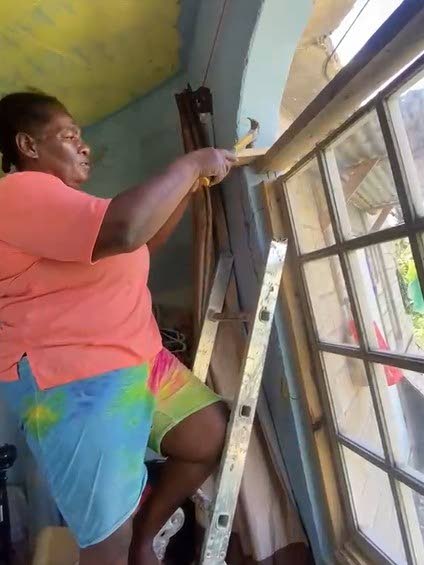 Janette Cameron, a resident of Canaan, St James, works on repairing a damaged window at her house, which suffered significant damage during Hurricane Melissa on October 28 last year and has still not been fully repaired since then.