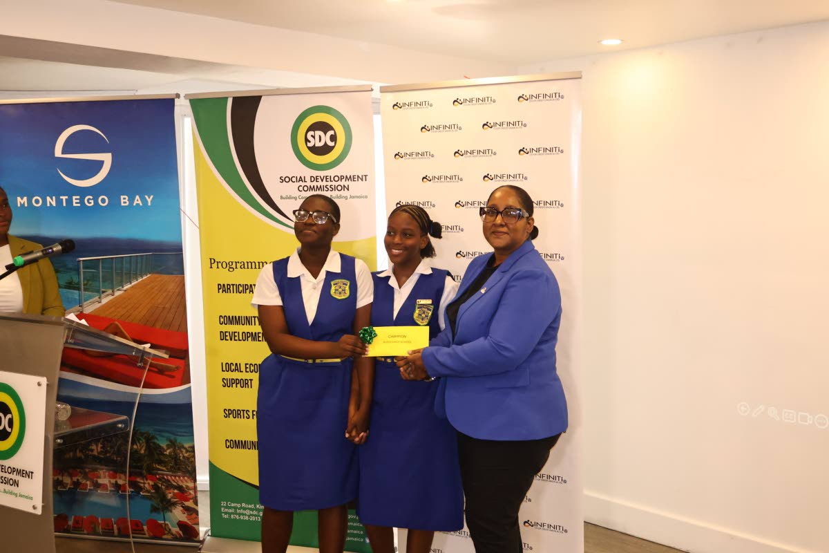 Rhamona Mohan-Samuels, chief operating officer at Infiniti Co-operative Credit Union, presents a first-prize envelope to Rusea’s High School’s Racene Small and Kathaleya Dixon, the operators of RK Sweet Treats, who came out as first-place winners.