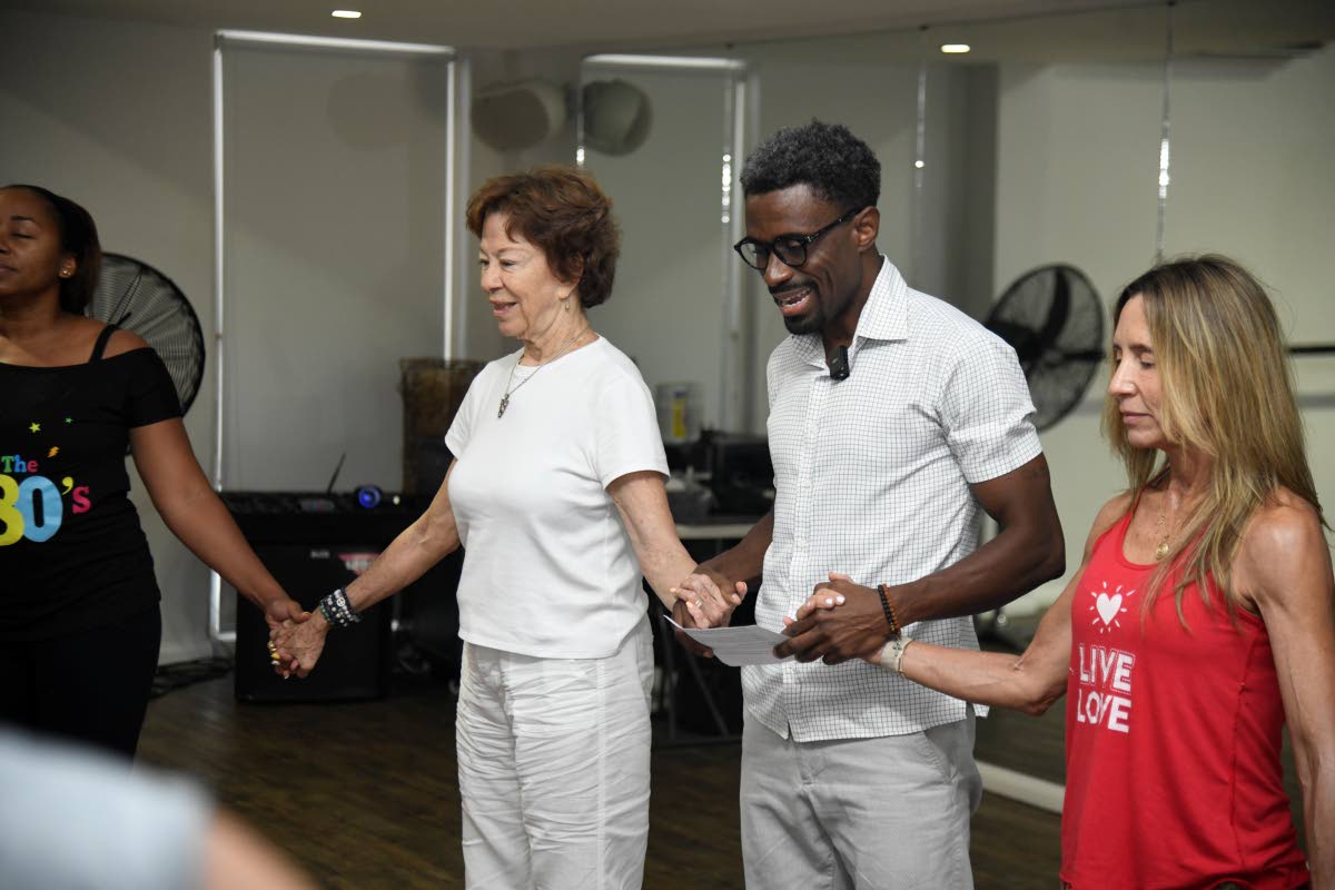 LeVaughn Flynn (centre) joins hands with Sanita Burrowes (left) following the 9D Breathwork session. 