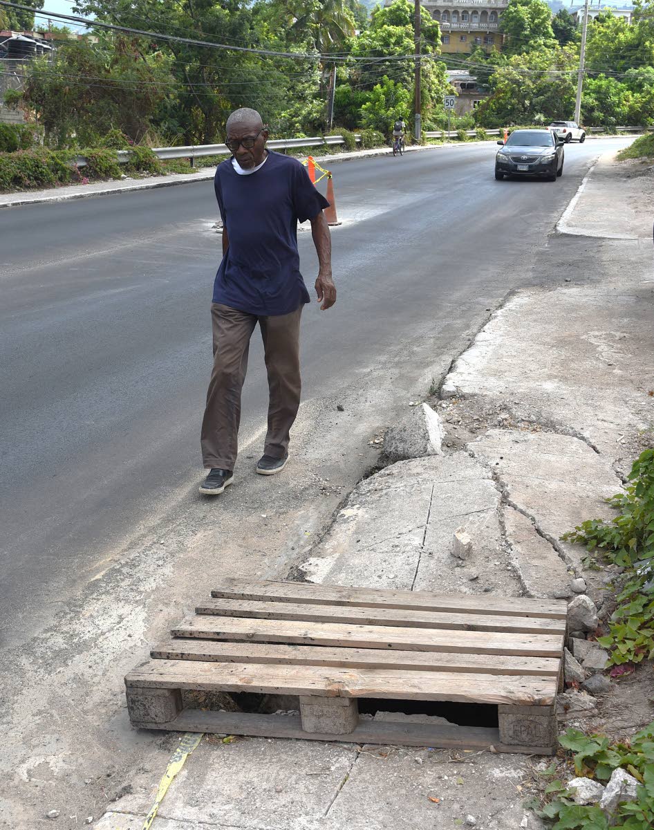 A visually impaired man walk past a compromised section of a sidewalk along Munroe road in St. Andrew that is currently being rehabilitated.