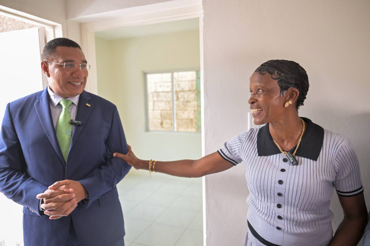 Prime Minister, Dr Andrew Holness (left), listens as New Social Housing Programme (NSHP) beneficiary, Andrea Burke, expresses her appreciation for her new three-bedroom home during the handover ceremony at 43 Rosemary Lane in Kingston on August 4.
