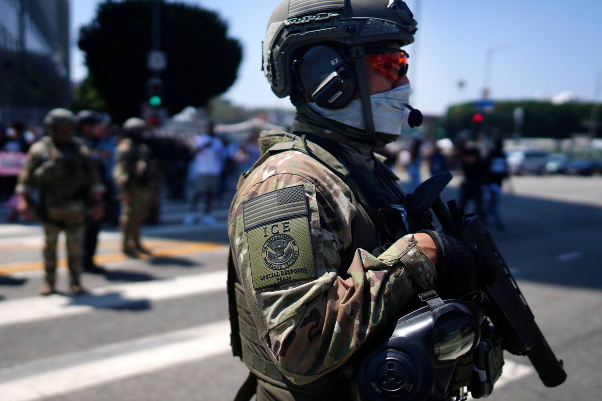 An ICE Special Response Team member stands guard outside the Metropolitan Detention Center, while protesters gather outside to denounce the US Immigration and Customs Enforcement, operations, in downtown Los Angeles. 