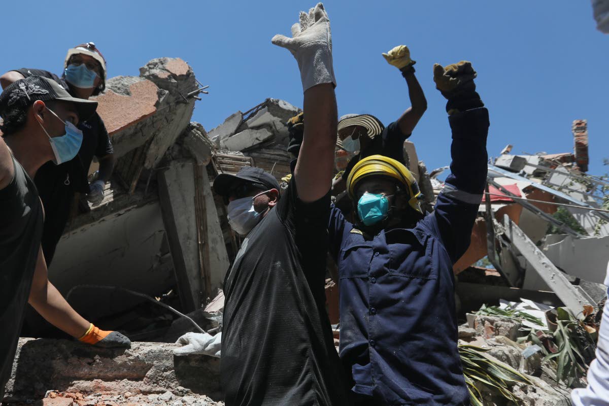 La gente pide silencio durante la búsqueda de supervivientes tras el terremoto que sacudió Cali, Colombia, el lunes 10 de agosto de 2026. (Foto AP/Santiago Saldarriaga)