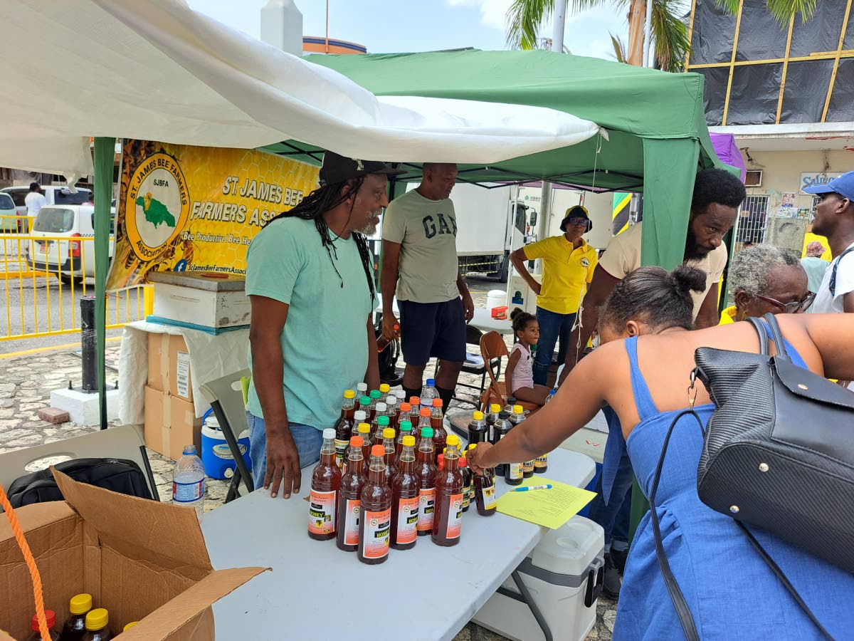 Dennis McKay (left), the chairman of the St James Bee Farmers Association, caters to patrons during the association’s fourth annual Healthy Lifestyle Day.