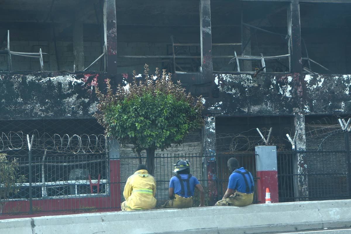 Firemen look at the fire-gutted Superior Parts building that was burnt out last Thursday. 
