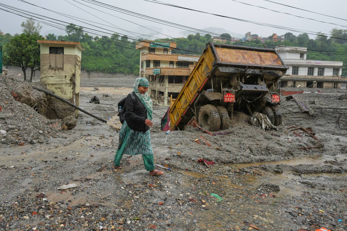 A woman walks through mud and debris left behind by flash flooding in Nepal’s Nuwakot district.