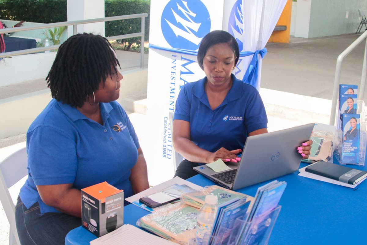 Kerry-Ann South (right), senior relationship manager at Mayberry Investments Limited, provides tailored financial information to Marsha McPherson (left), information technology specialist at Christel House Jamaica. They are pictured at the Mayberry Investm