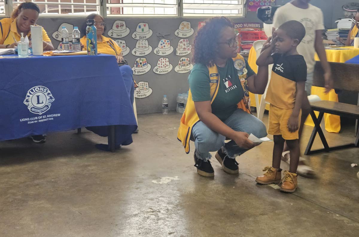 Janelle Walker, a member of the Lions Club of St Andrew, tests the vision of a child attending the 15th staging of the Rotary Club of Trafalgar New Heights’ health fair for the community of Maverley recently. The event was held at the Maverley Primary an