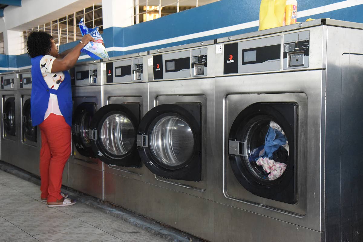 A worker operates one of the washing machines at Spic N Span Express Laundromat on Lady Musgrave Road in St Andrew.