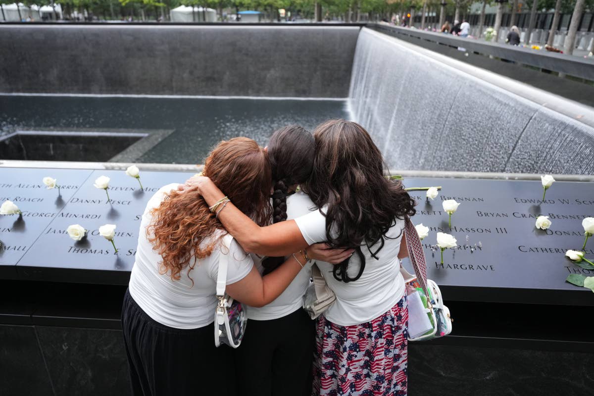 Rosanne Spirito, 49, and daughters Sabrina, 22, and Amanda, 20, who lost their sister Catherine Lisa LoGuidice, stand at a reflecting pool on the 25th anniversary of the September 11, 2001, terrorist attacks, Friday, Sept. 11, 2026, in New York. (AP Photo/