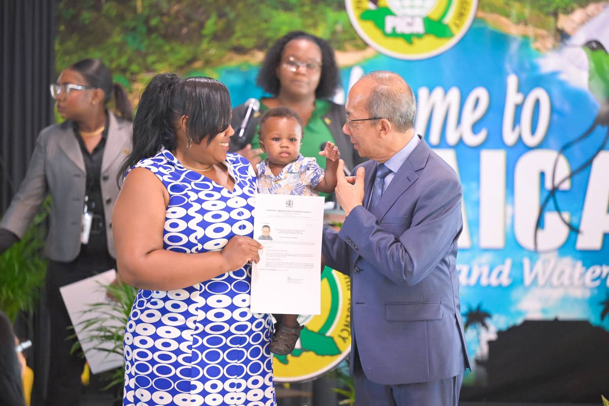 Deputy Prime Minister and Minister of National Security and Peace, Dr Horace Chang, shares a moment with Jamaican citizen, Sharmaine Campbell Burrell (left), and her son, Kejaun Burrell, as they display a certificate formalising his citizenship during the 