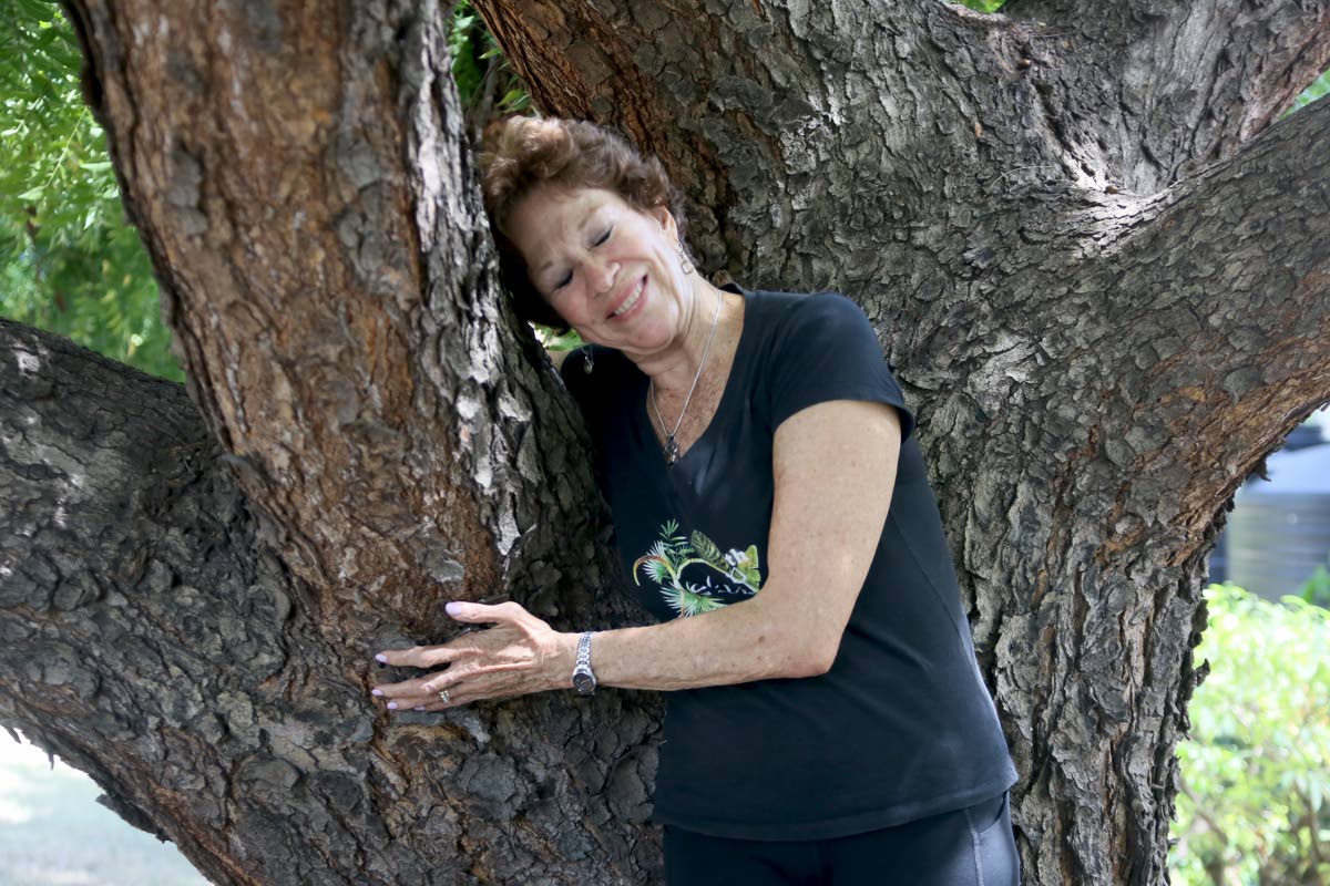 Sonita Abrahams Burrowes embraces the neem tree in front of Afya Yoga Studio, which replaced a mango tree her mother planted at the studio’s former home on Bamboo Avenue. 