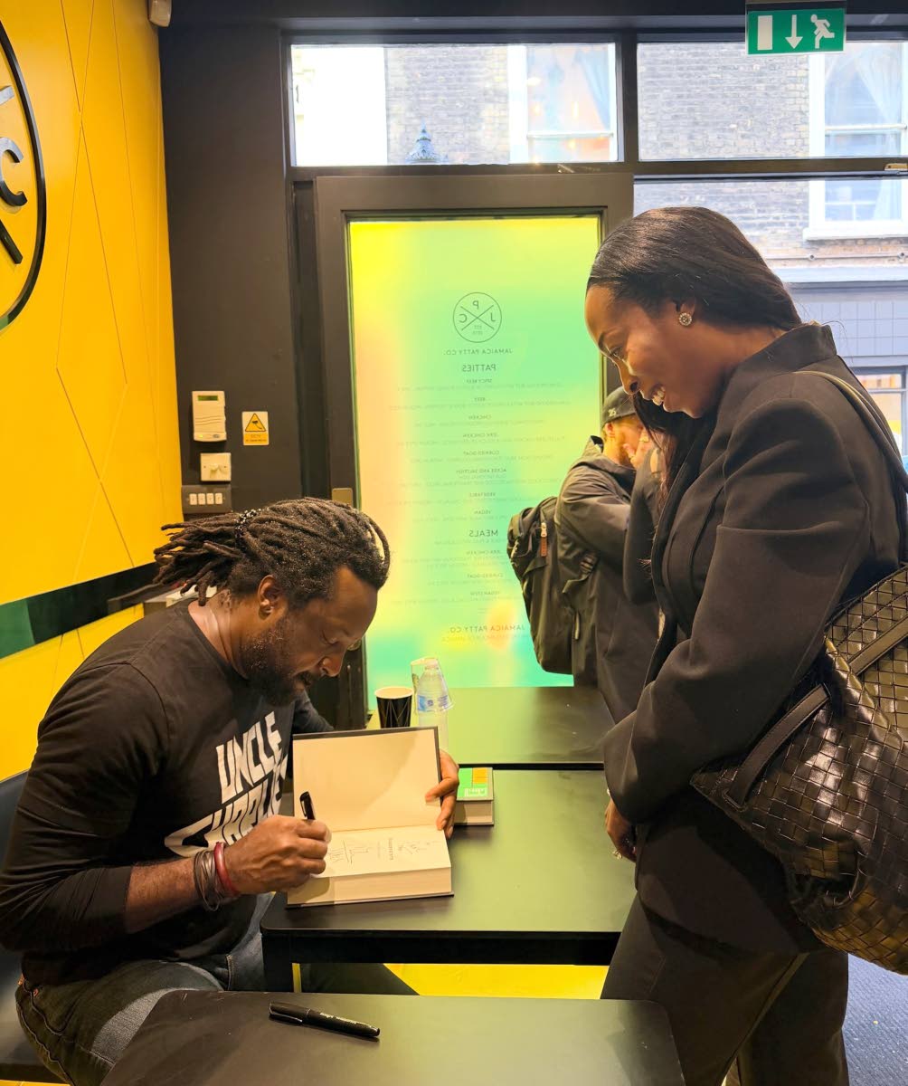 Marlon James signs his Booker Prize shortlisted book The Disappearers for a visitor at the book signing event at the Jamaica Patty Company restaurant.