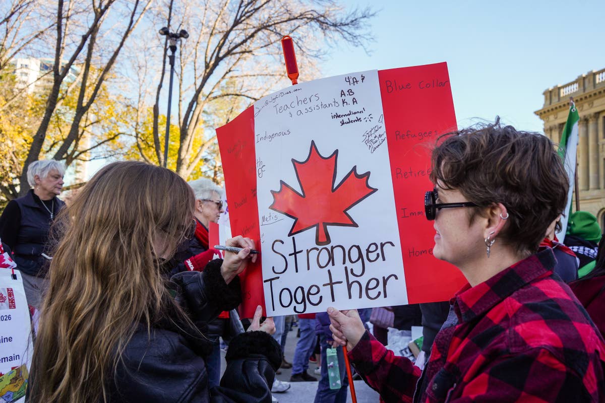 A supporter writes on a protest sign during a pro-Canada rally in Edmonton, Alberta, Sunday, Oct, 18, 2026. 