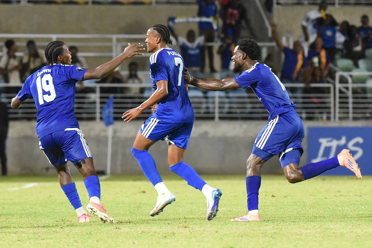 Mount Pleasant’s Nickalia Fuller (centre) celebrates with teammates Warner Brown (left) and Kyle Ming after scoring in yesterday’s Caribbean Cup semi-final football match against Trinidad and Tobago’s Club Sando at Sabina Park.