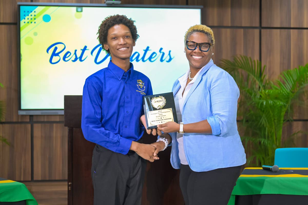 Marcia Brown-Bailey (right), director of population and health at the Planning Institute of Jamaica (PIOJ), presents the trophy for Best Tertiary Debater to Joshua Atkins of the University of Technology (UTech) Knights.