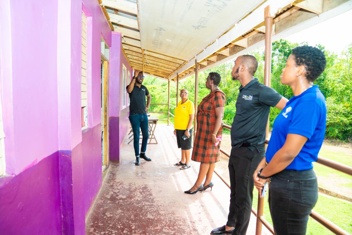 Omar Wright (left), lead for environment and community development initiatives at the JN Foundation, inspects a section of the boxed eave that was damaged by Hurricane Melissa at the Kendal Primary School in Manchester. Inspecting the eave along with him i