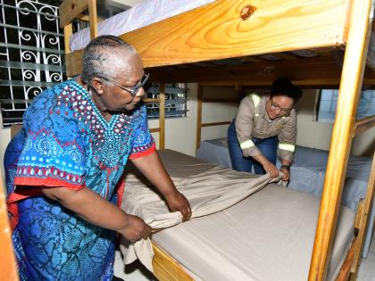 Annie Dawson Children’s Home founder Ivaline Nickie gets assistance in making the bed in one of the girls’ dormitories from Timara Jackson, who has been an avid supporter of the home for the last two years. 