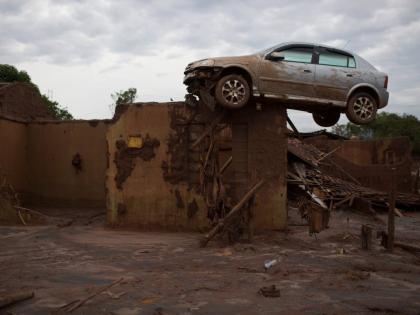 In this November 23, 2015 photo, a car sits on top of a wall of a home, destroyed when a dam burst in Bento Rodrigues, Brazil.