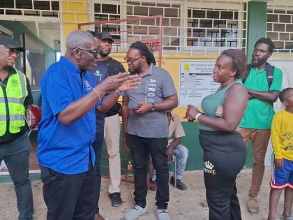 Desmond McKenzie (second left), minister of local government and community development, addresses a concerned resident at the Petersfield High School shelter yesterday, following a break-in at the facility. 