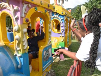 Keisha Sutherland (right), waves to her daughter Shakeira Morris (left) as she rides on the train at the Funland at Hope Gardens in St Andrew during the Digicel Foundation Christmas Treat for special needs children yesterday.  