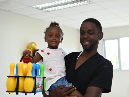 Little Khaylya Harvey, after receiving her bowling set, poses with her father, Dane Harvey, during the Montego Bay Free Zone and Global Services Association Jamaica post-Hurricane Melissa Christmas treat for Catherine Hall and Westgreen residents in St Jam