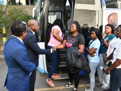 Labour and Social Security Minister Pearnel Charles Jr (second left) shakes hands with farm worker Zeneice Nixon at a send-off ceremony for 95 workers who departed the island for Toronto, Canada, last April under the Canadian Seasonal Agricultural Workers 
