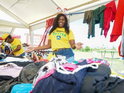 A JN Foundation volunteer shows off some of the items inside the thrift shop established on the football field of the William Knibb Memorial High School last Sunday. The shop was one of the highlights of an event organised and hosted by FYI Consultancy Gro